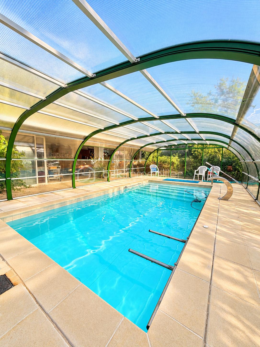 Piscine turquoise sous verrière végétale.png