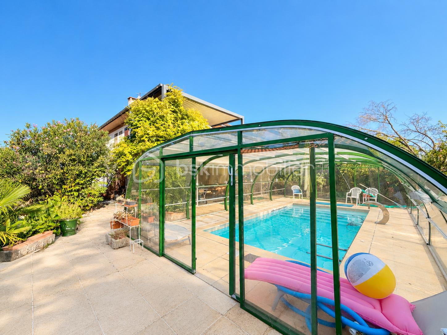 Piscine turquoise sous verrière verdoyante.png