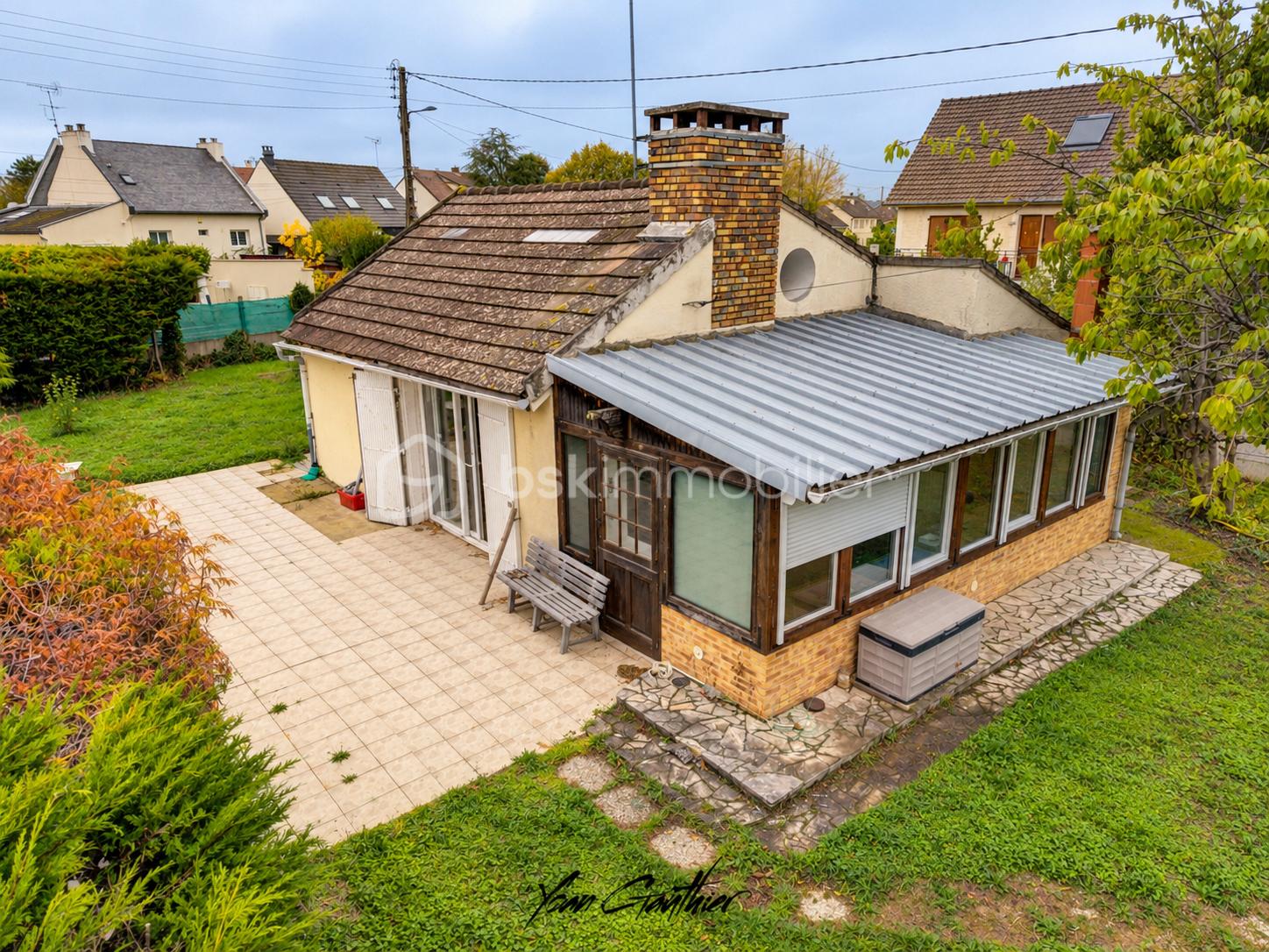 Vue aérienne d’une maison de banlieue enveloppée de verdure.png
