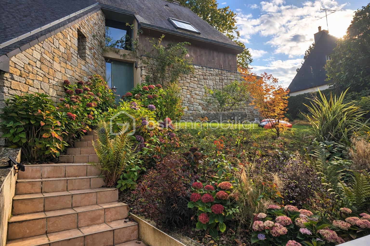Jardin ensoleillé devant une maison en pierre.png