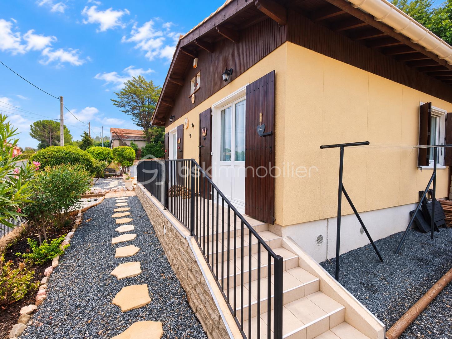 Maison beige et jardin ensoleillé.png