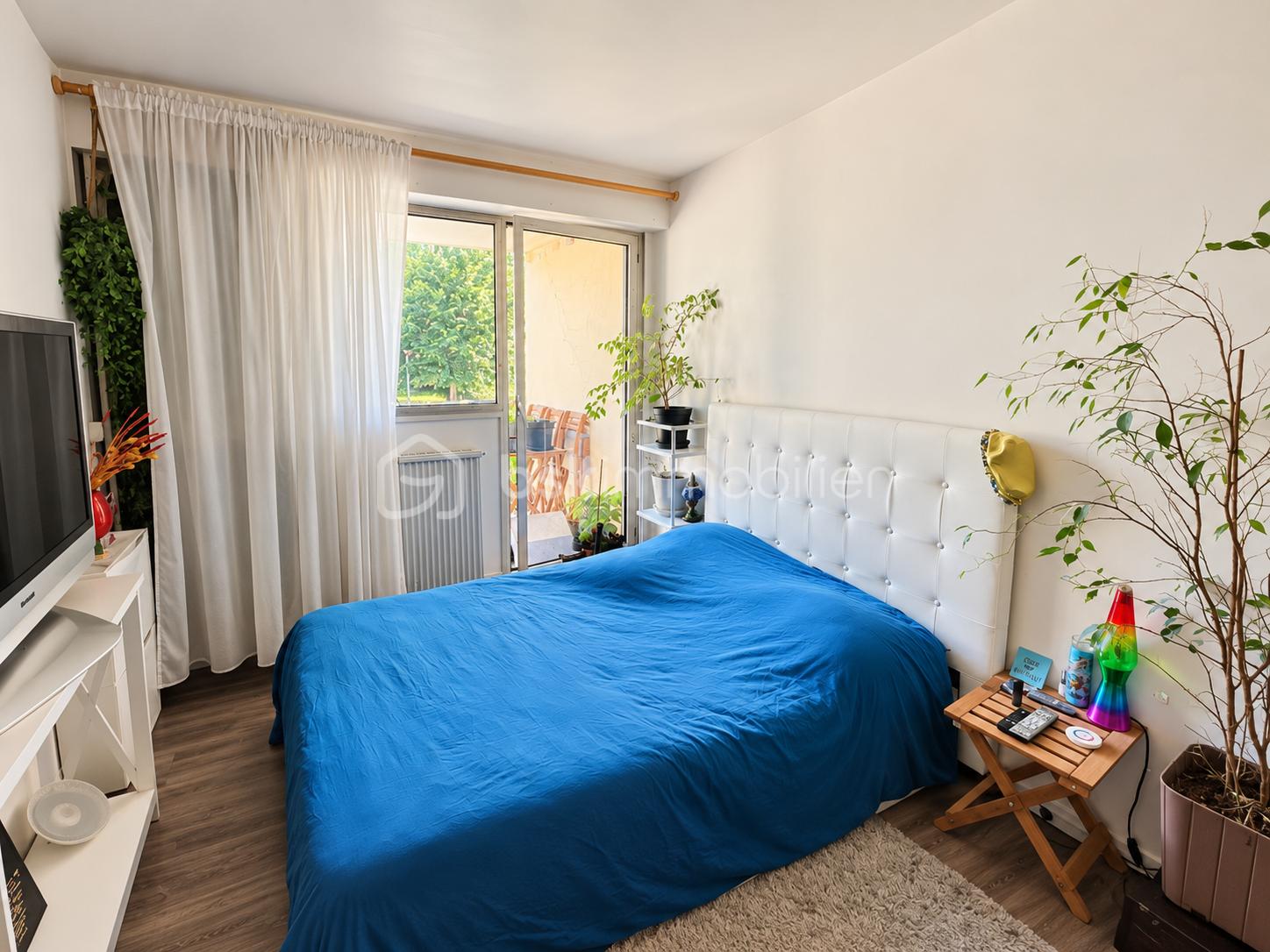 Chambre lumineuse au lit bleu et plantes.png