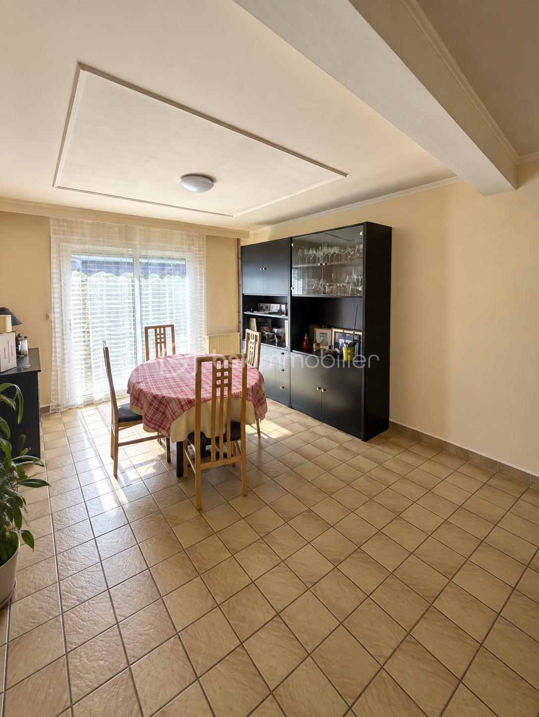 Salle à manger ensoleillée avec vaisselier sombre.png