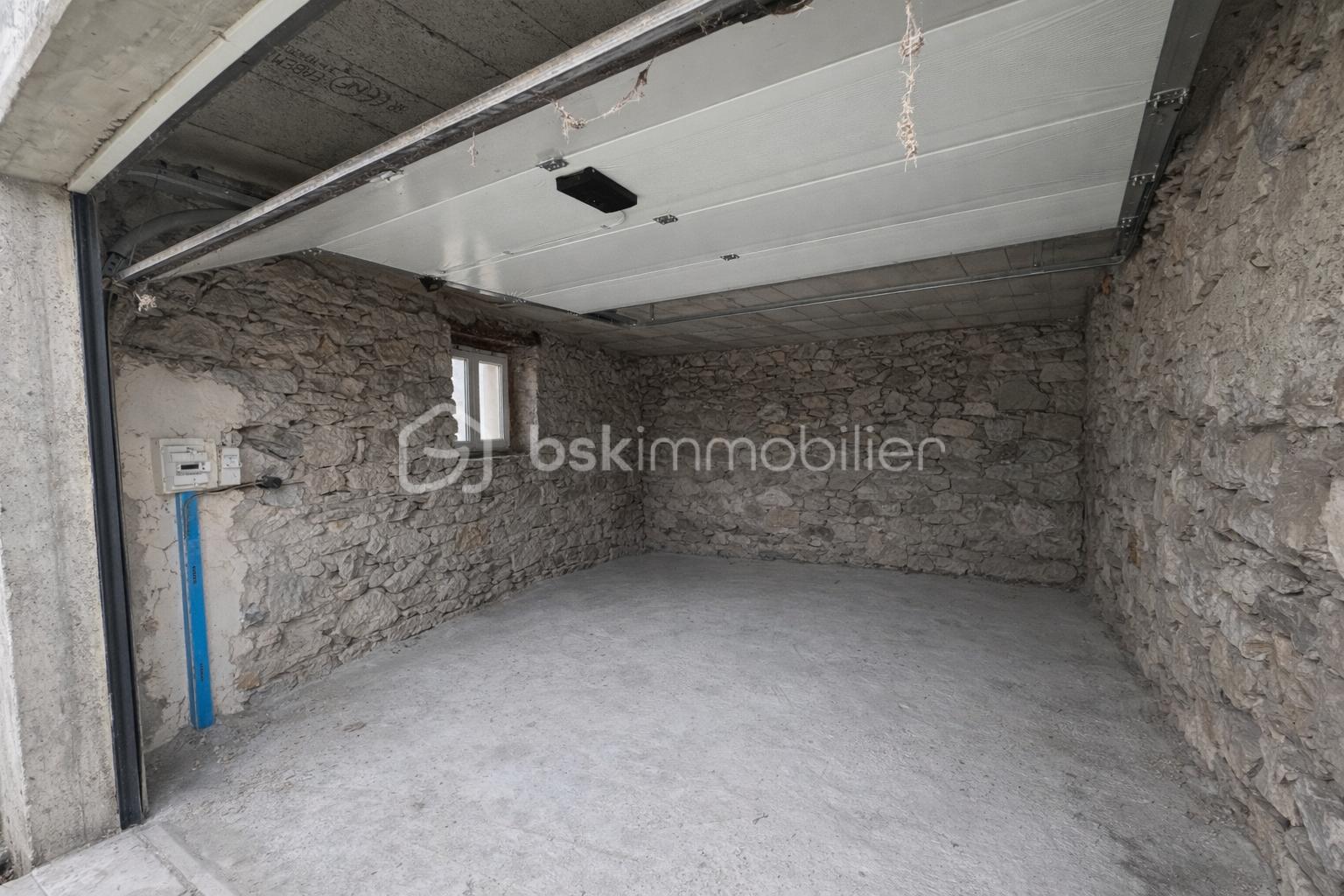 Maison de 134 m² - Garage vide avec murs en pierre.png
