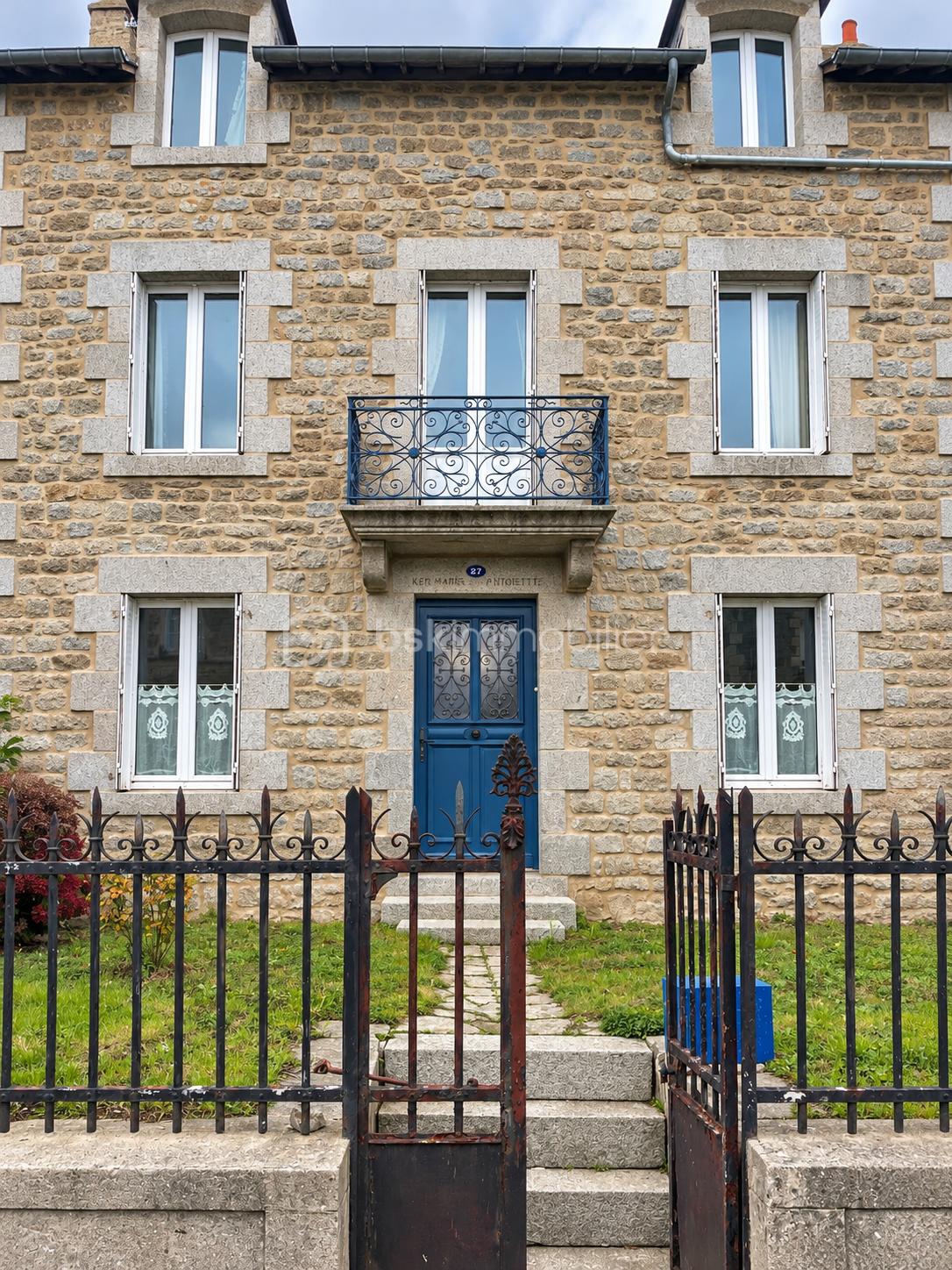Façade en pierre avec balcon et portail forgé.png