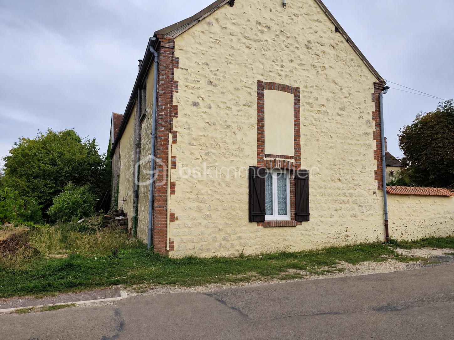 Façade rurale en pierre sous ciel gris.png