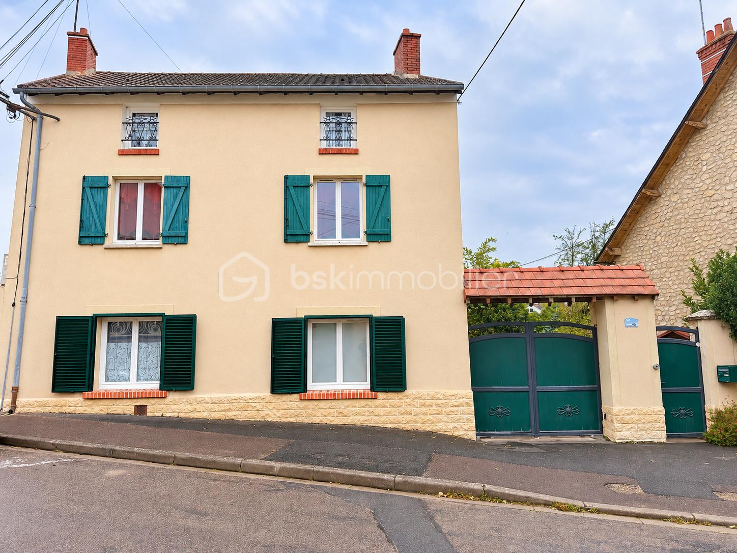 Façade beige aux volets verts et portail numéroté 32.png