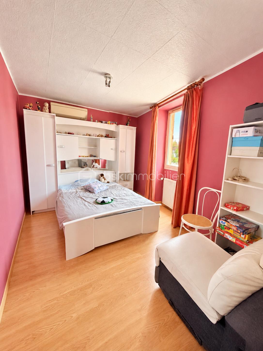 Chambre rose avec lit et rangements blancs.png