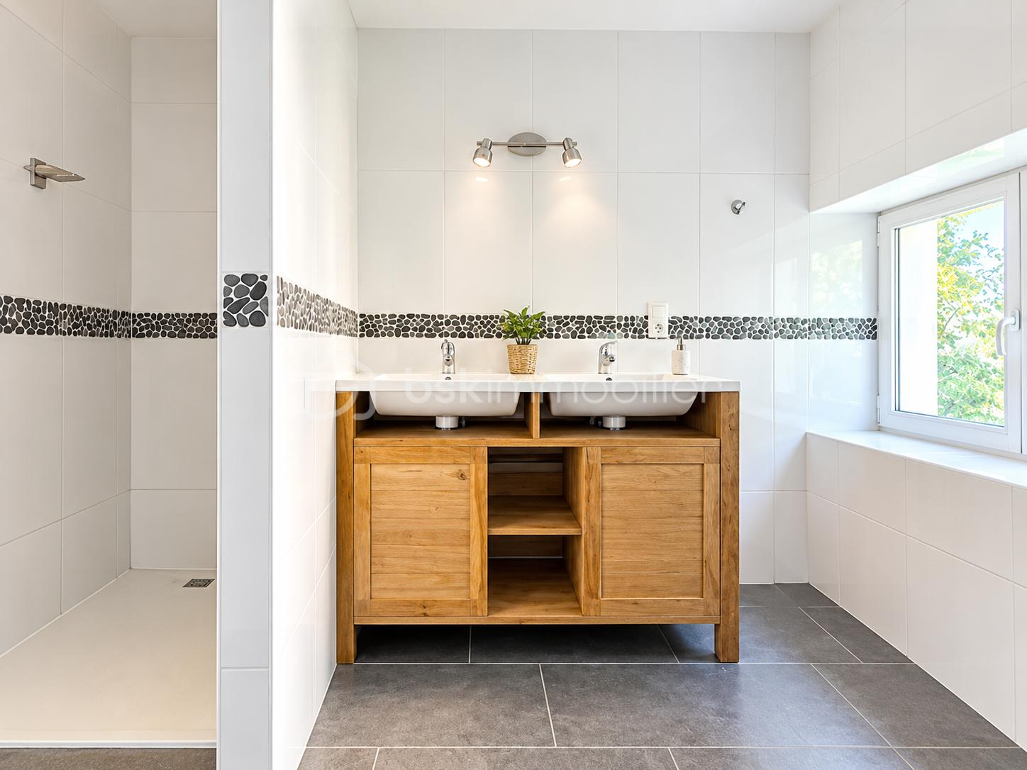 Salle de bains moderne avec double vasque et douche ouverte.png