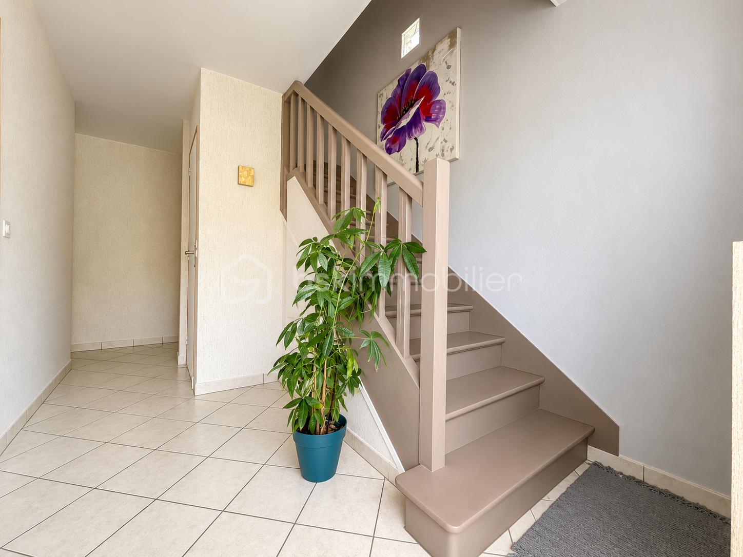 Entrée lumineuse avec escalier taupe et plante verte.png