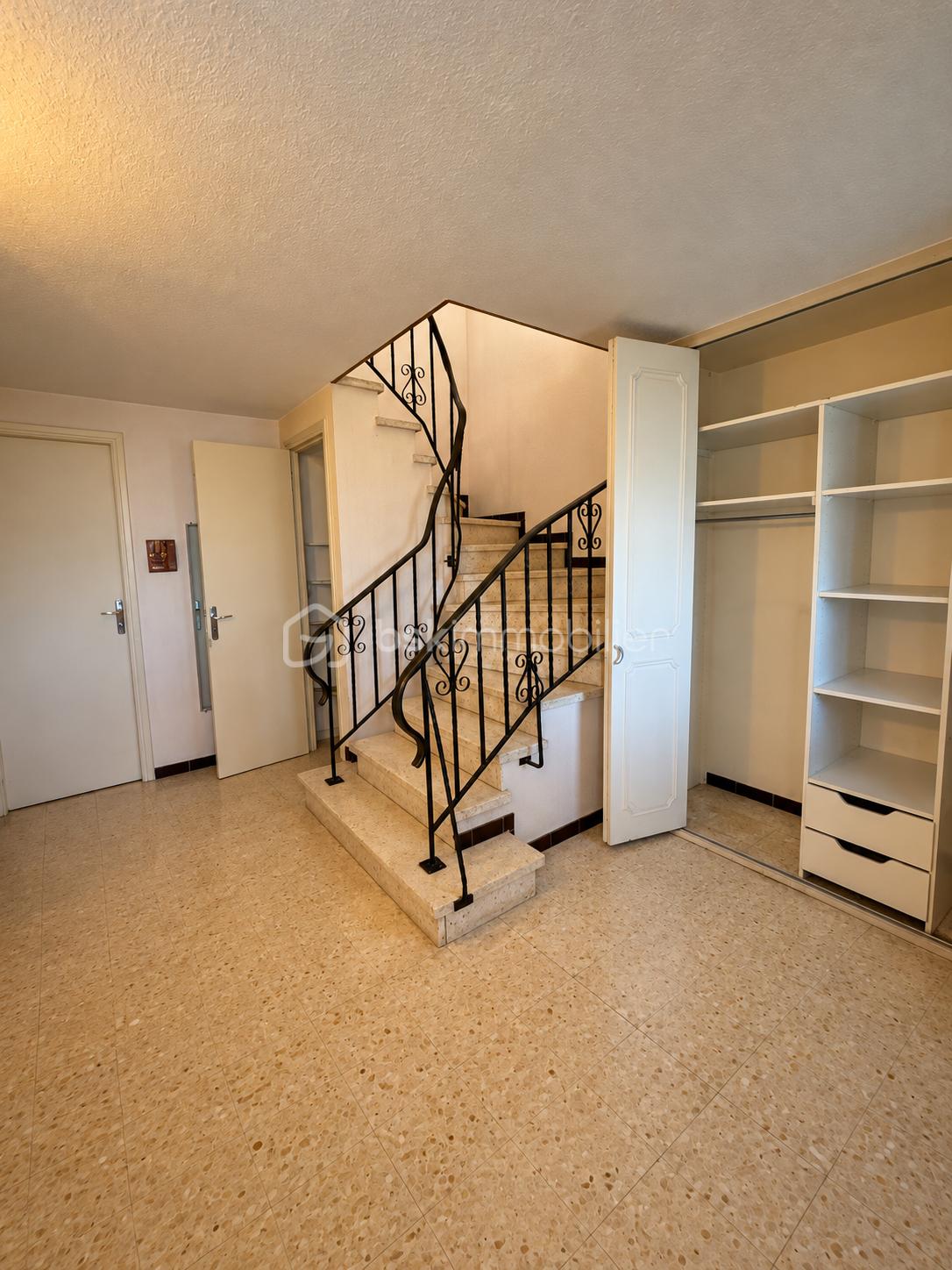 Entrée chaleureuse avec escalier en fer forgé.png