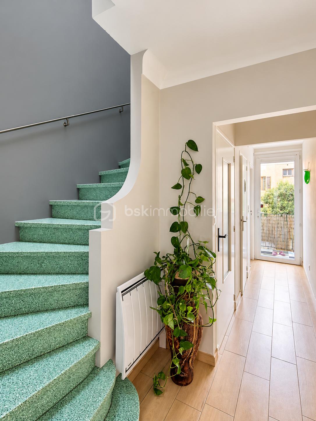 Couloir moderne avec escalier vert et plante suspendue.png