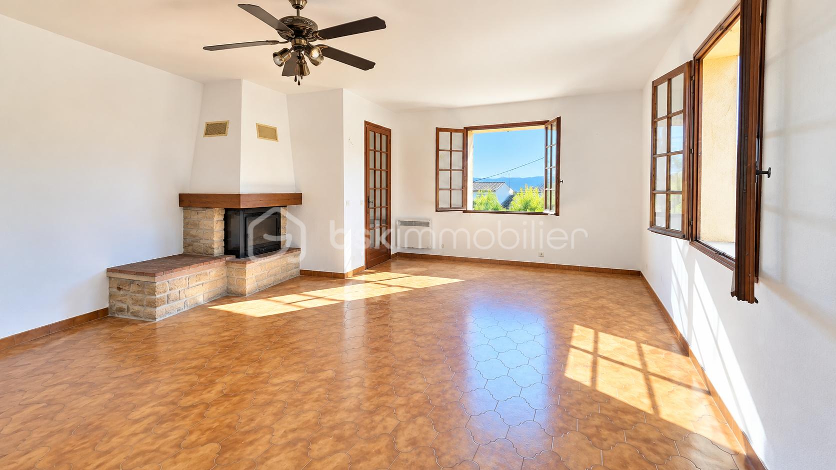 Salon baigné de soleil et cheminée rustique.png