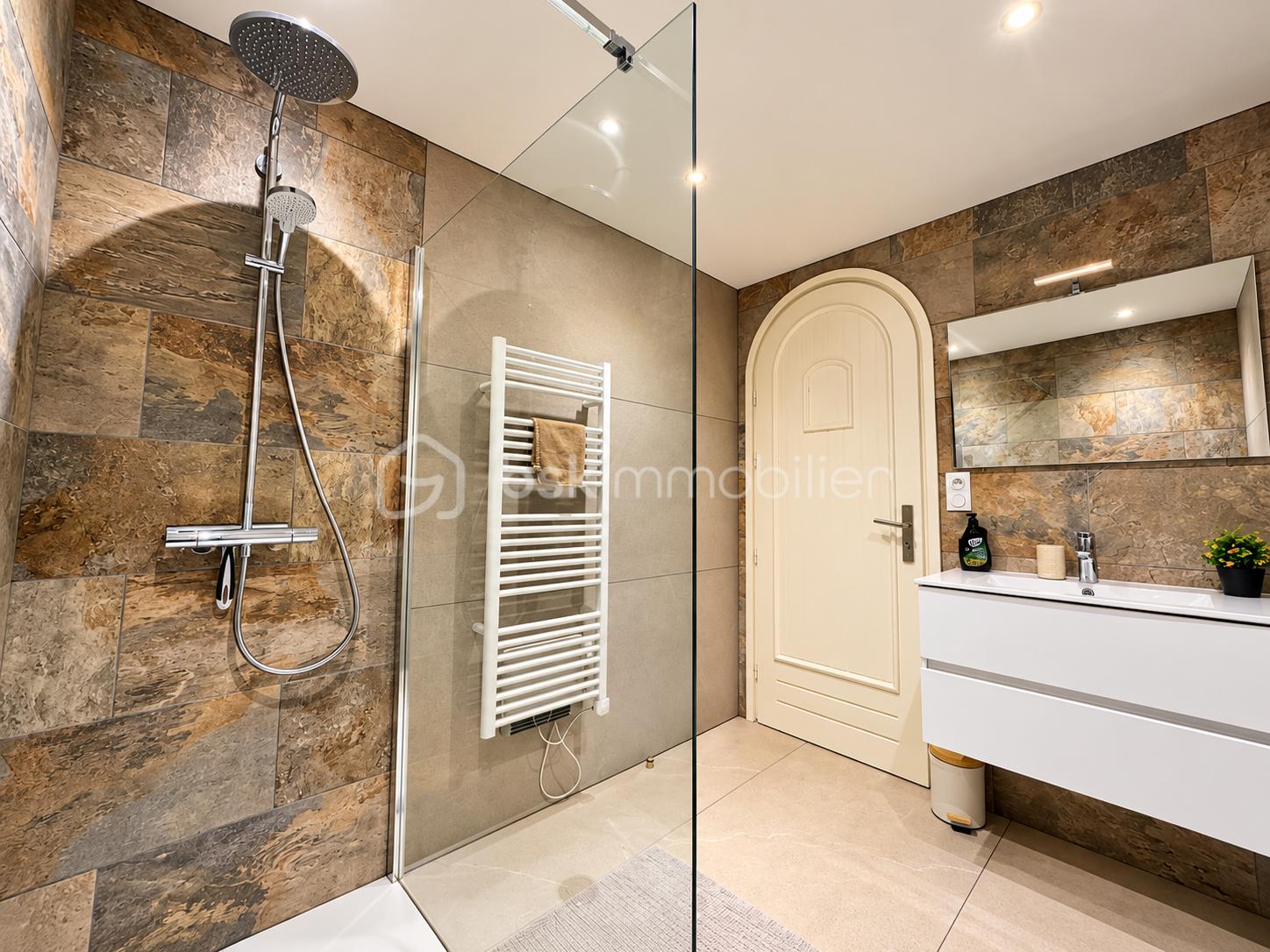 Salle de bain moderne avec douche vitrée et vanité.png