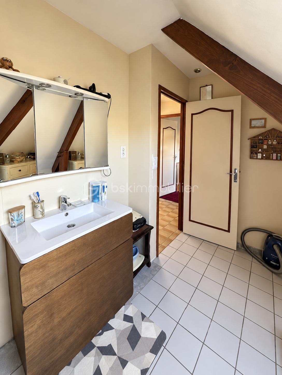 Salle de bain mansardée chaleureuse et rangée.png