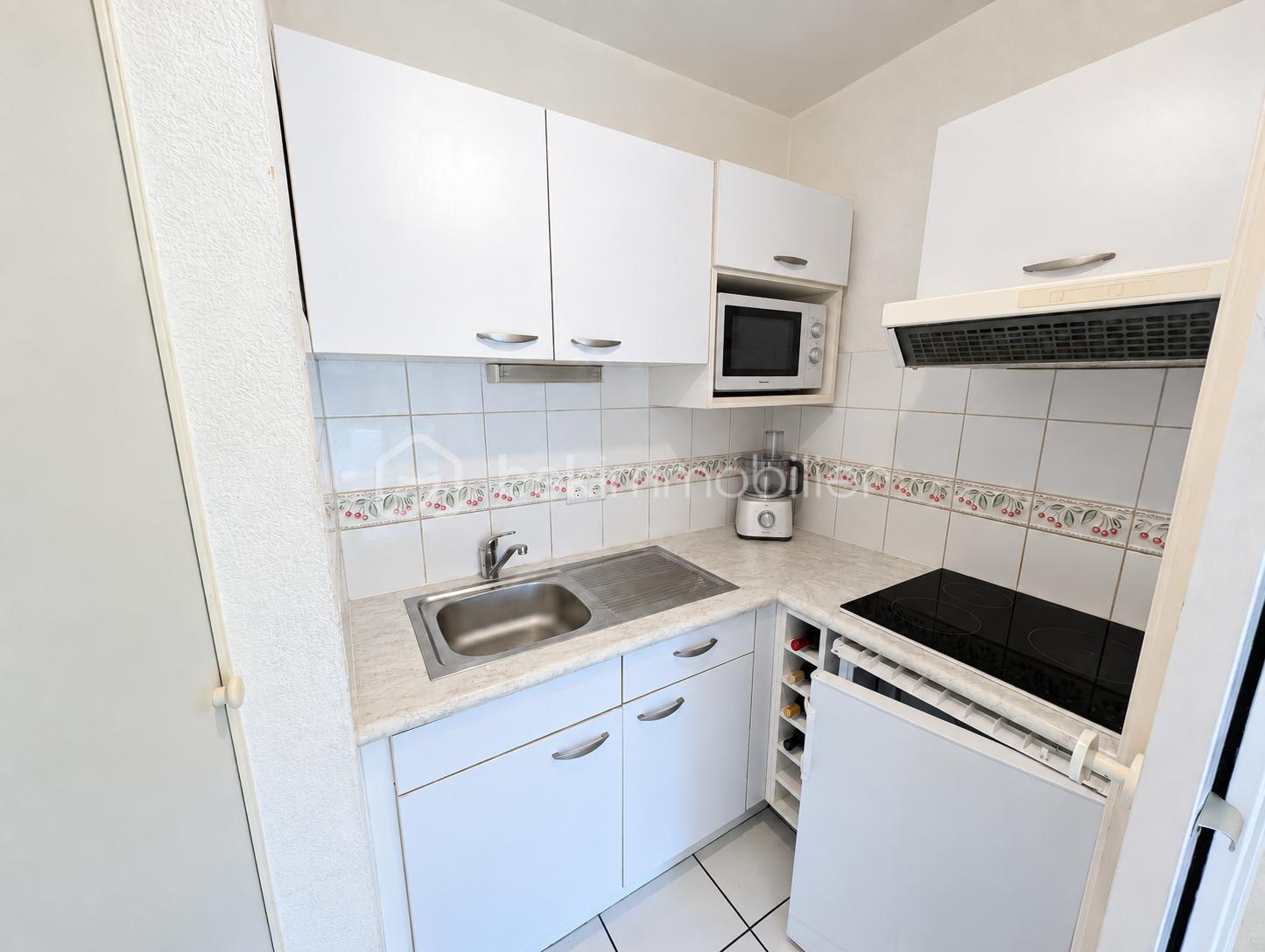 Kitchenette épurée, micro-ondes et bouteilles de vin.png