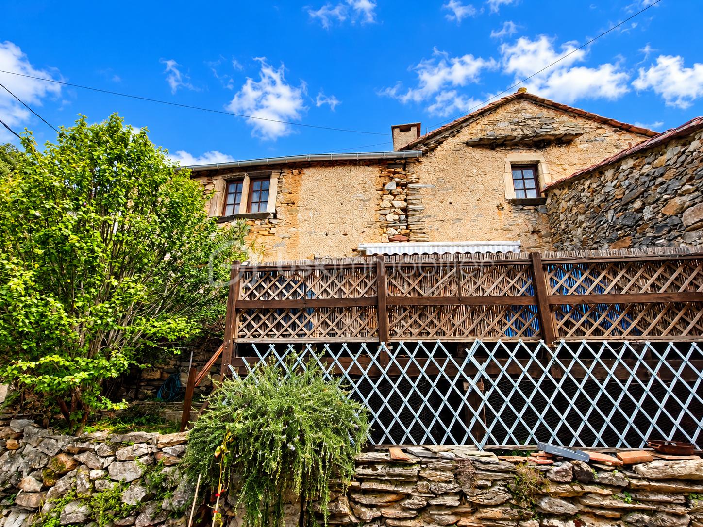 Maison rurale en pierre sous ciel bleu.png