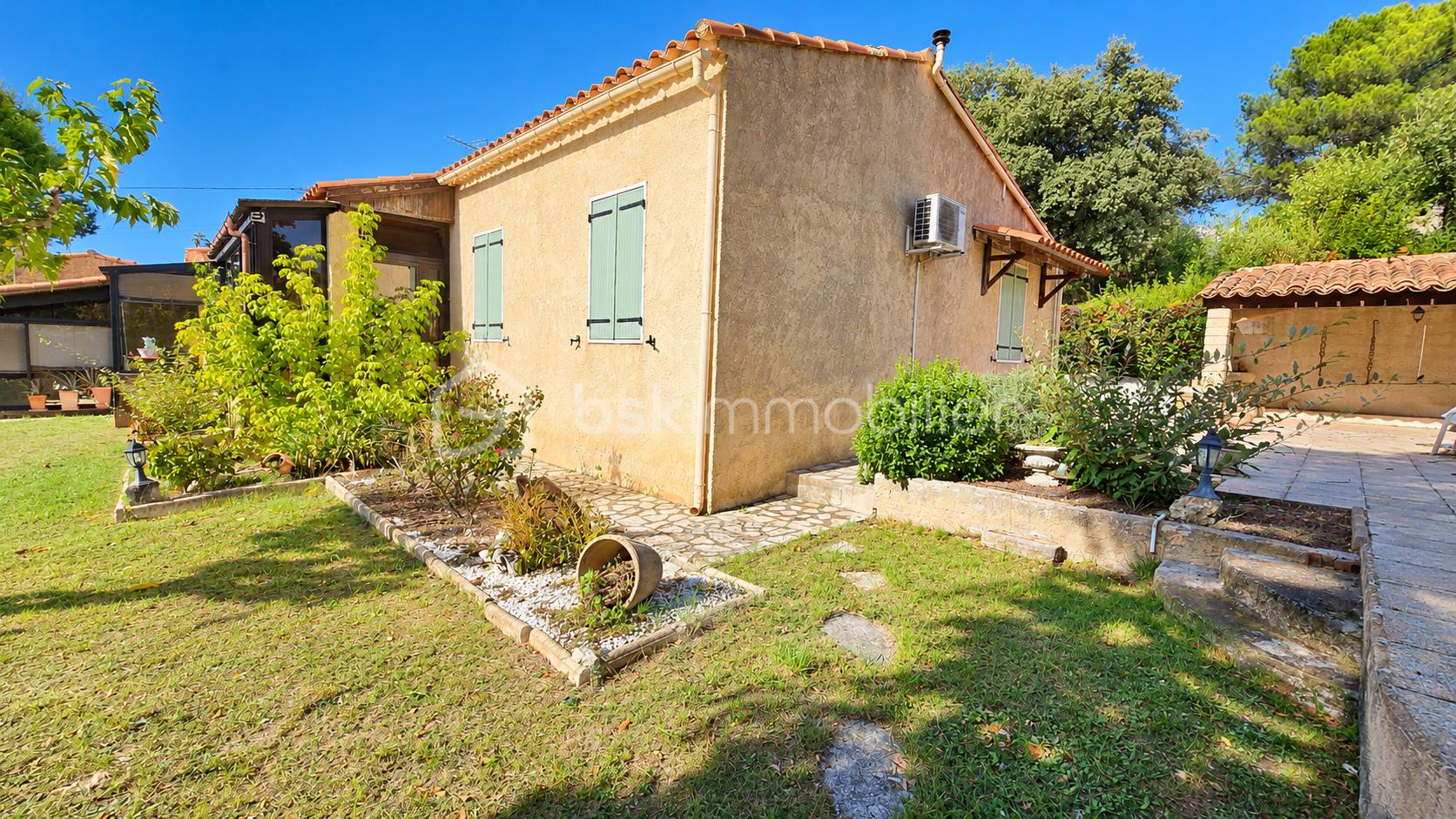 Jardin méditerranéen ensoleillé devant une maison en pierre.png