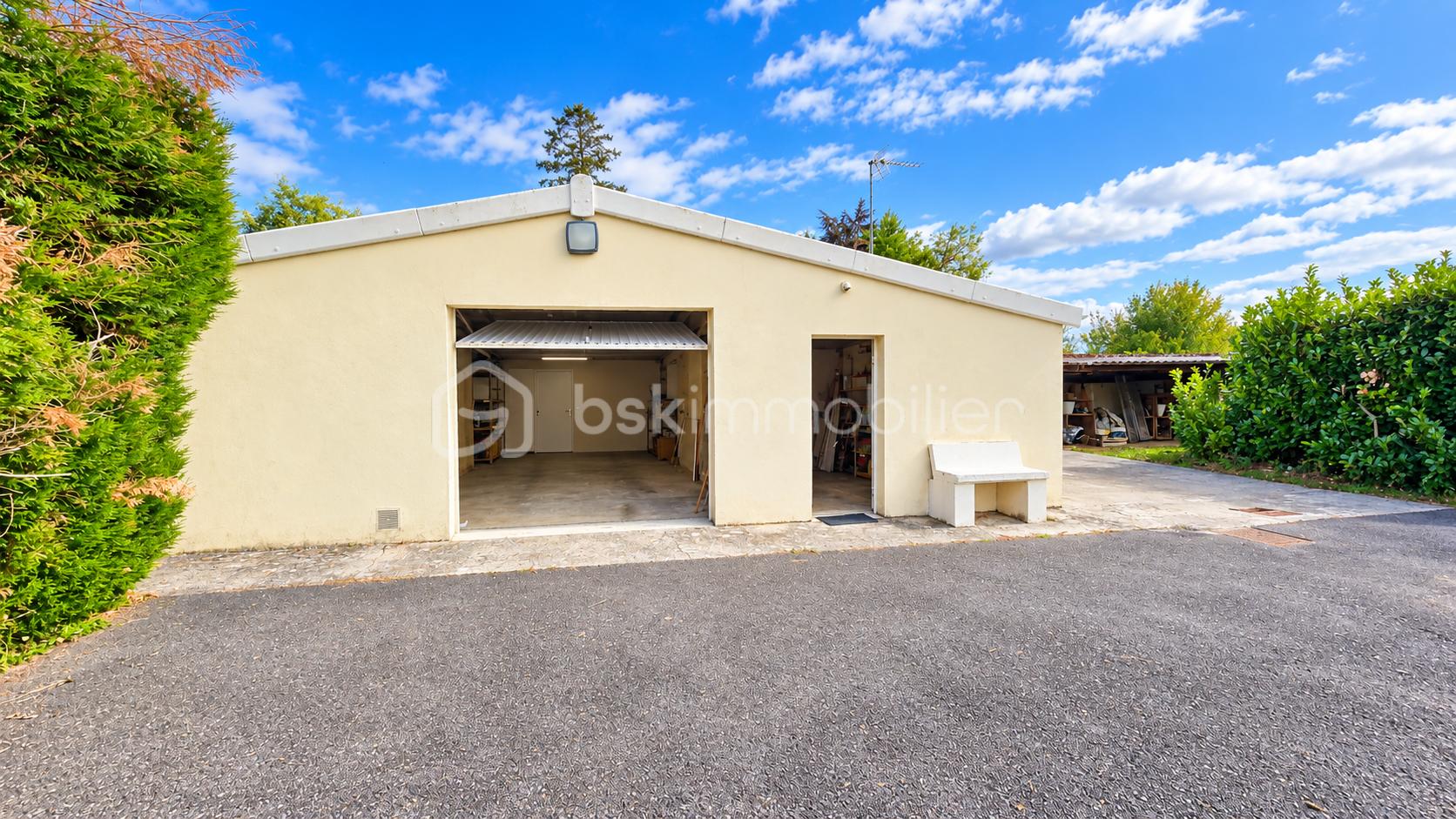 Garage-atelier ouvert dans un jardin verdoyant.png